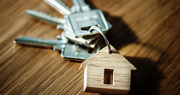 Key chain with a small wooden house, symbolizing real estate law and property transactions.